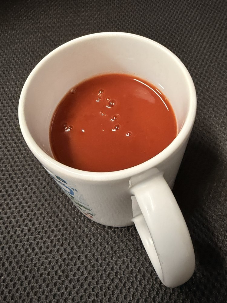 白いマグカップに注いだデルモンテ 食塩無添加トマトジュース。とろみのある濃い赤色